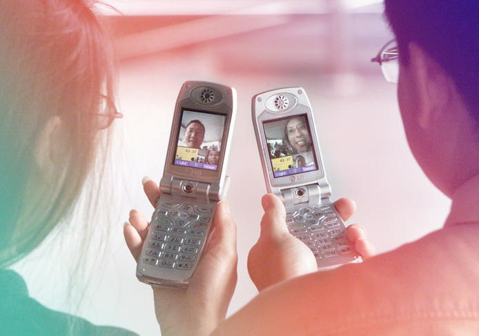 Two 3G mobile phone users using the mobile video conferencing features to communicate in a posed photo taken in 2002.